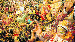 Artistes dressed up like Radha and Krishna celebrate Holi at a temple in Jalandhar on Thursday.
