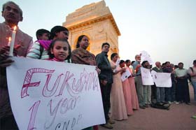 People pay tributes to those killed in the Japan tsunami and Fukushima nuclear disaster on their first anniversary during a candlelight vigil at India Gate in New Delhi on Sunday