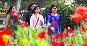 College girls walk past red poppy flowers in Jalandhar on Wednesday.