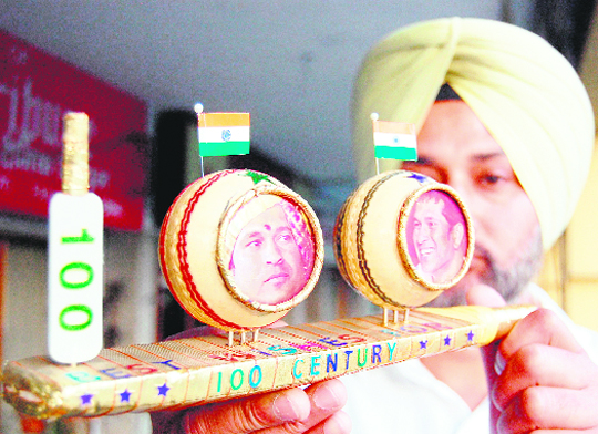 Miniature artist HS Gill congratulates Sachin Tendulkar on hundredth century with his creation in Amritsar on Friday.