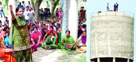 A protester (left) raising slogans against the state government near a water tank at Bhokhra village on Sunday; protesters climb atop the water tank.