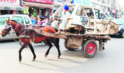 A horse cart carries the body of a car on busy Copper Road in Amritsar
