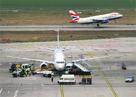 An airplane takes off as another is parked on the tarmac of the Geneva International Airport on Tuesday