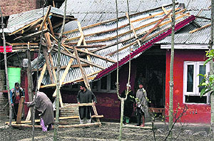 Residents salvage timber pieces of a roof shattered by strong winds in Srinagar on Tuesday