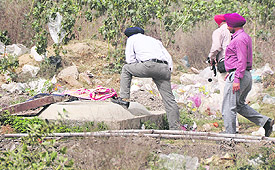 Police officials inspect the spot where an unidentified body was recovered near Keys Hotel on the Pakhowal road in Ludhiana on Tuesday.