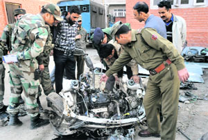 Army and police personnel examine the wreckage of a car in Anantnag on Thursday. 