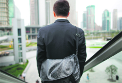 A businessman rides an escalator in the financial district of Pudong in Shanghai in this Sept 2011 file photo. Many foreign investors in China have been hit by a steady rise in wages, which puts them in the same boat as many US businesses in China responding to a survey released on Monday by the American Chamber of Commerce