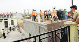 MC workers raze an illegal construction during a demolition drive at Burail in Chandigarh on Monday.