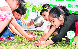 Kids plant a sapling at Sati Kund, Kankhal, in Haridwar on Sunday.