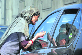 A woman seeks alms at a traffic light in Gurgaon.