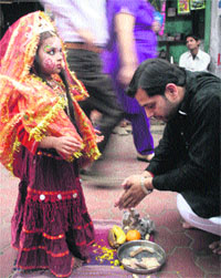 A devotee worships Gunjan, dressed as a goddess, near a temple in Jammu. 