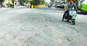 Commuters negotiate potholes on Ladowali Road in Jalandhar.