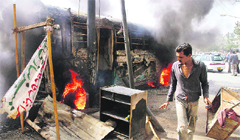 A man walks past a bus gutted after violent protests erupted in Karachi 