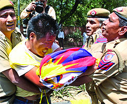 Policemen detain a Tibetan activist protesting against the visit of Chinese President Hu Jintao near the Taj Palace in New Delhi on Thursday