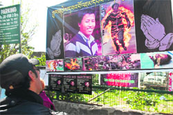 A foreigner looks at a poster of Jamphel Yeshi, who committed self-immolation in Delhi, at McLeodganj in Dharamsala on Thursday