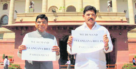 TDP's Nama Nageswara Rao (L) holds a placard demanding introduction of the Telangana Bill in Parliament, in New Delhi on Thursday. 