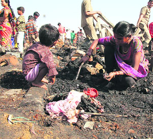 Slum-dwellers look for their belongings in the debris of their hutments gutted in  a devastating fire in Sector 57 of Gurgaon on Friday. 