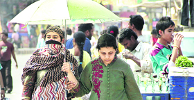 Girls use an umbrella on a hot summer afternoon in Jalandhar on Sunday.
