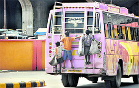 Street children take a ride by hanging unto the rear of a bus, unmindful of the risk, in Ludhiana.
