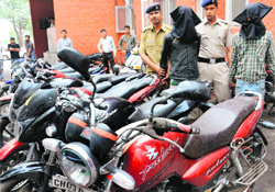 Members of a gang of thieves in police custody and the stolen motorcycles recovered from them at the Mani Majra police station in Chandigarh on Monday. 
