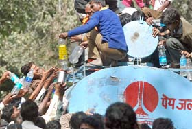People scramble to take water from an NDMC tanker at Jantar Mantar to quench their thirst as the temperature rises to 38.3 C, in New Delhi on Monday