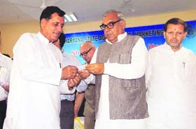 Chief Minister Bhupinder Singh Hooda presents a digital smart card to a farmer at the Farmer Business Information Centre at the new grain market in Karnal on Monday