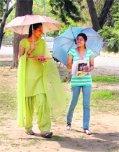To get respite from heat, students take shelter under umbrellas in Ludhiana on Monday. 