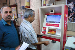 Jagbhushan Sharma (left), chief manager of the Bank Street branch of PNB, explains how to operate a Cash Deposit Kiosk. 
