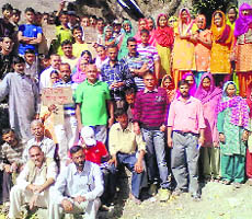 Villagers stage a dharna in protest against the anti-people policy of the project management at Palampur on Friday. 