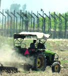 A farmer ploughs his field near the border fence in the Jammu region
