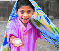 A delighted boy holds a cluster of hail stones in Hyderabad on Friday