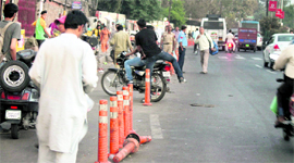A motorcyclist makes way through the damaged plastic dividers in the busy Bikram Chowk area of Jammu on Saturday.