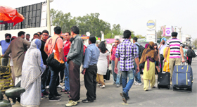 People wait outside the Jammu airport in the absence of a passenger shed.