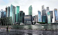 A worker cleans the ground along Marina Bay overlooking buildings of the financial district in Singapore. The island states economy is expected to expand by 2.5% in 2012 from 4.9% last year, higher than earlier estimates as a surge in fourth-quarter pharmaceutical exports cushioned a drop in electronics, the government said