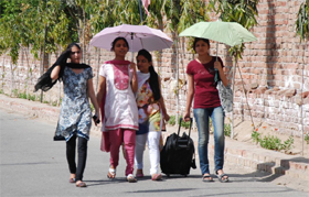 As the sun beat down hard, hiding behind their dupattas and umbrellas, these young girls try their best to beat the heat in Bathinda on Sunday. 