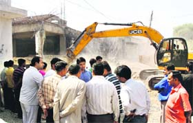 A JCB machine demolishes a four-storeyed building in Gurgaon on Sunday