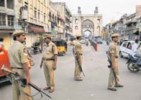 Armed policemen guard a street near Charminar after shops were closed on request by the police following clashes between two groups in Hyderabad on Sunday
