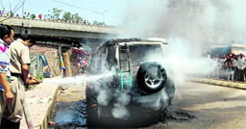 Fire personnel douse flames after a Tata Sumo catches fire at the Inter-State Bus Terminus in Jalandhar on Sunday.