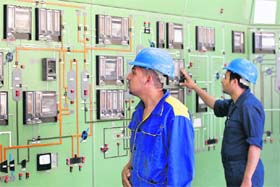 Workers inspect equipment in the control room of the al-Doura petroleum refinery in Baghdad