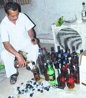 A man fills spurious whisky into branded bottles at a rented house in Karnal on Monday night. As many as 500 bottles were seized in a raid.