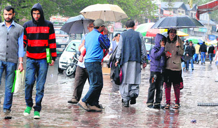 Tourists enjoy a rainy spell while shopping on the Residency Road in Srinagar on Monday