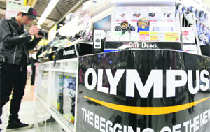 A customer looks at a digital camera next to an ad for Olympus at an electronics store in Tokyo on Tuesday.