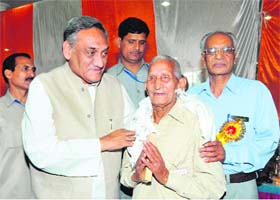 Chief Minister Vijay Bahuguna honours a pensioner in Dehradun on Tuesday