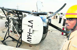A security personnel stands near the helicopter that crash-landed on the rooftop of an apartment building
