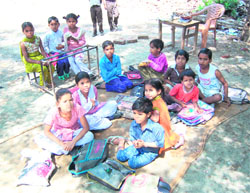 Students sit on dirty mats in the absence of proper seating infrastructure