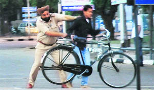 A policeman on VIP duty thrashes a cyclist who was trying to cross a road at the Sector 11-5 roundabout before Manmohan Singhs visit to Panchkula on Friday.