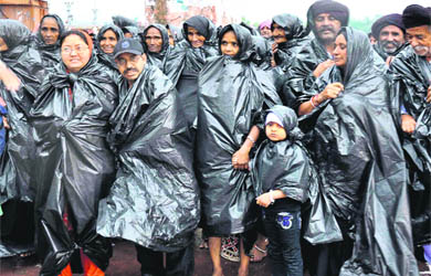 Pilgrims from Gujarat protect themselves from rain at the Ganga ghat in Haridwar on Friday. 