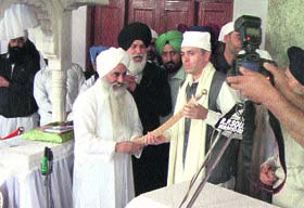 Mahant Manjeet Singh, head of Dera Sant Pura Nangali Sahib, presents a sword to Chief Minister Omar Abdullah in Poonch on Friday