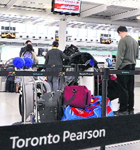 Air Canada passengers line up at the baggage check-in counter at Pearson International Airport in Toronto on Friday