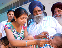 A volunteer administers polio vaccine drops to a child at a booth set up in a school on the 100-feet road in Bathinda on Sunday